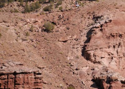 Photo from a distance of dirtbike tour guide Jim Stanley atop a cliff band in the high desert.