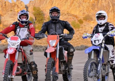 Dirtbike touring company ENduro Ranch hosts riders at Hartman Rocks with sunset on the rock outcrops behind riders.