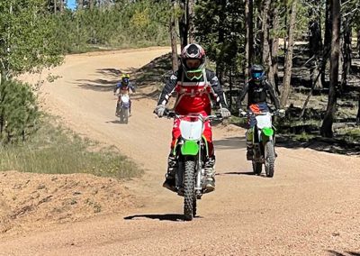 3 Young dirtbikers wind along a forest ride