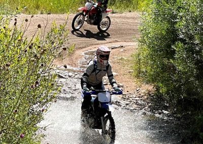 Picture of girl on dirtbike training while riding through a creek