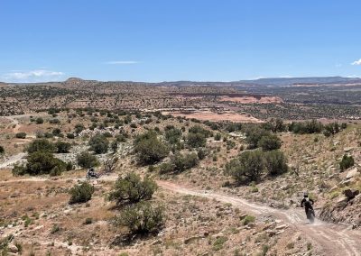 Two riders drop down a road into the red rocks and canyons of Rabbit Valley