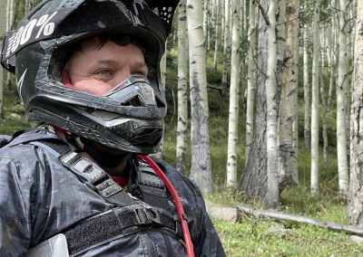 Photo of dirtbiker smiling after riding on a vacation amongst a huge aspen grove.
