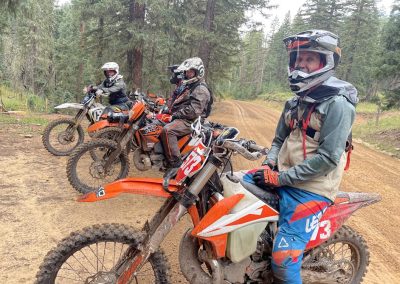 Shot of four dirtbikers taking a break from a day of riding deep in the forest.