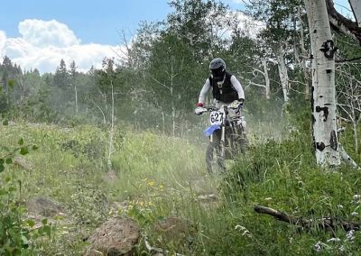 Dirtbike guide Ian Leeming rides amongst aspens, tall grasses and flowers.
