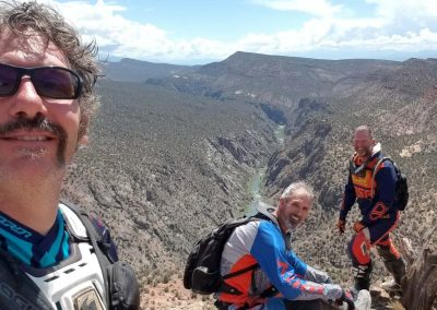 Dirtbiking vacation riders rest looking down on a river.