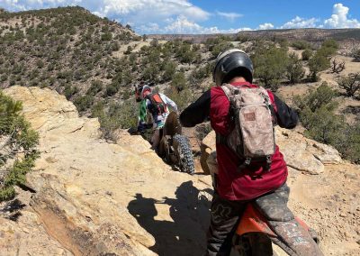 Shot from behind dirtbikers on vacation going between rocks into canyon.